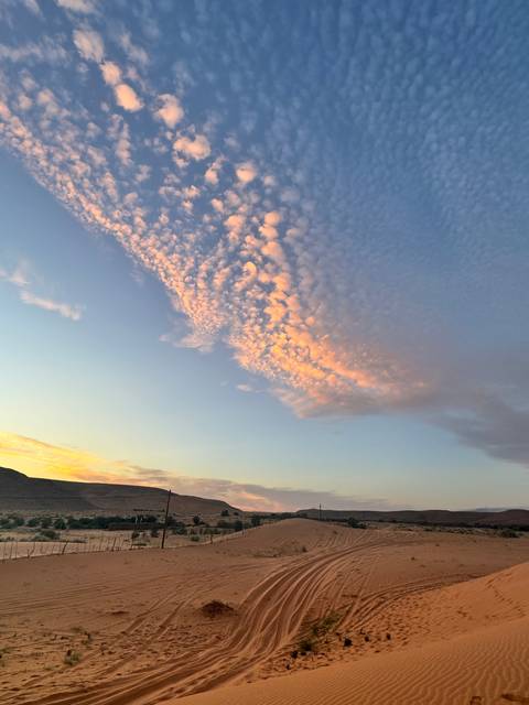 Desert landscape with tracks and a colorful sunset sky.