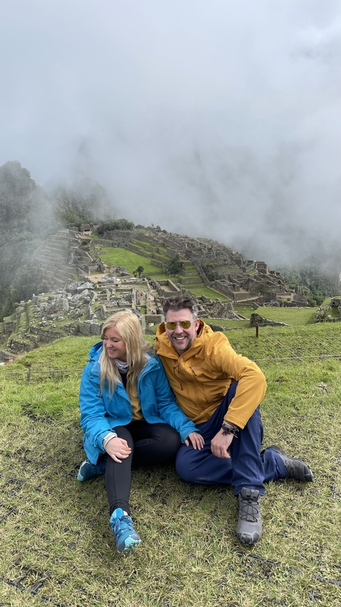 Two people sitting with Machu Picchu in the background.