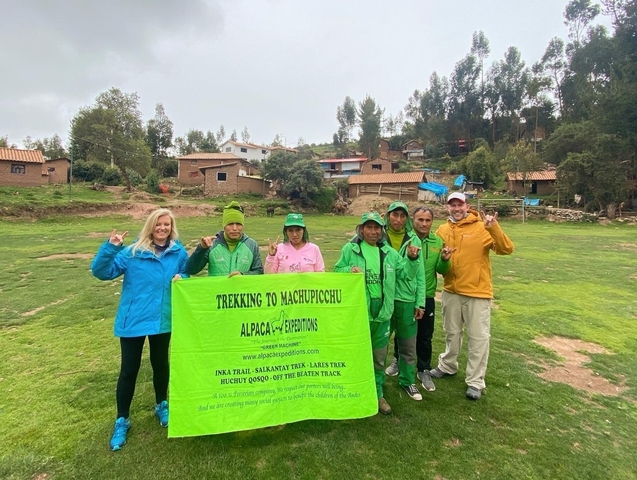 Group of people posing with a banner in a field.