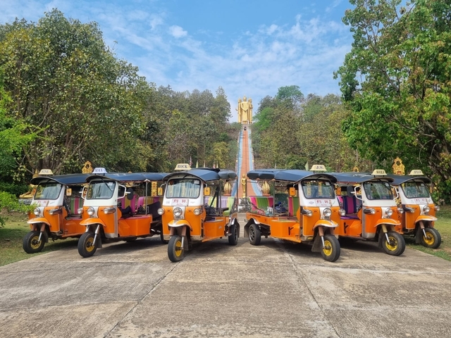 Group of tuk-tuks lined up in front of a temple.