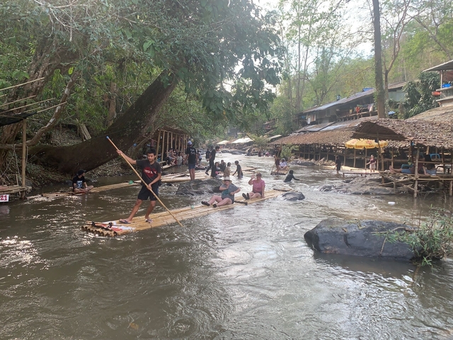 People rafting on a river surrounded by trees.
