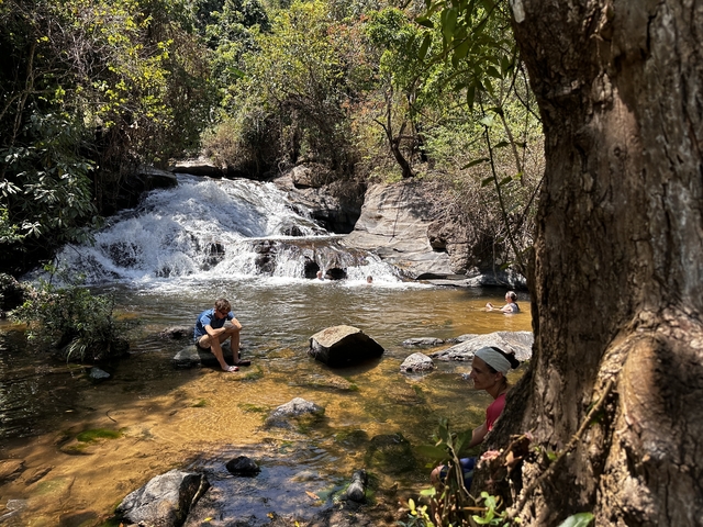 People enjoying a waterfall in a natural setting.