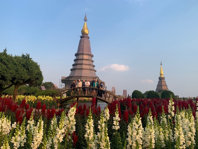 Group of people in a garden with stupas and flowers.