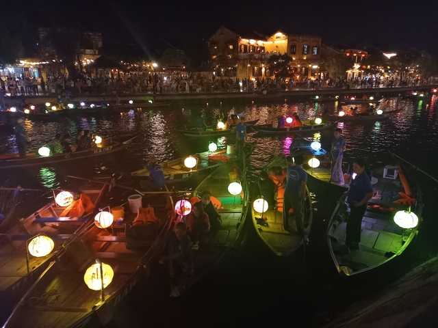 Illuminated canoes with lanterns in a vibrant night market.
