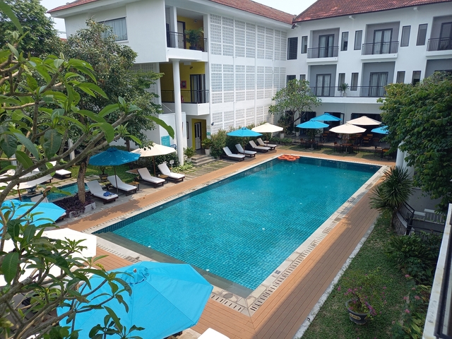 Outdoor swimming pool at a hotel with sun loungers and umbrellas.