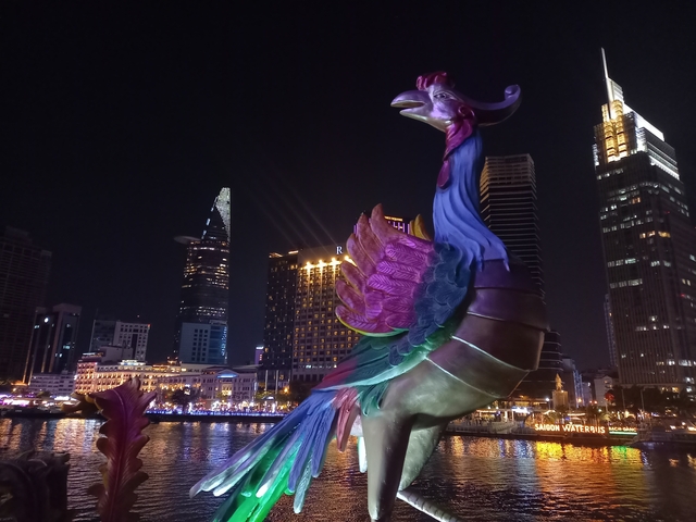 Colourful rooster sculpture against a vibrant night skyline.