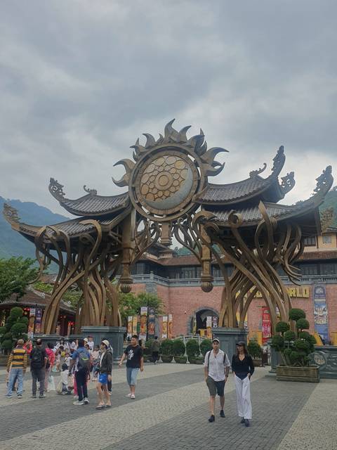 People standing near a large clock-like sculpture.