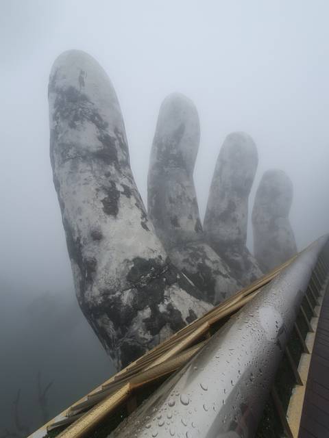 A close-up view of a large stone hand emerging from the fog.