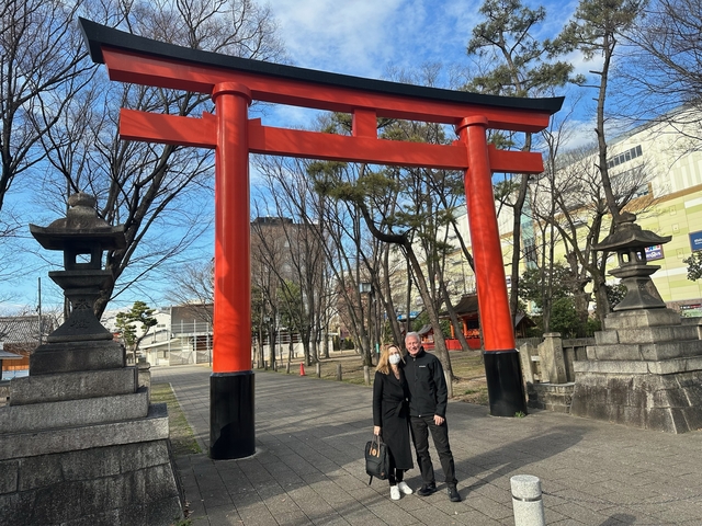 Couple standing under a large Torii gate in Japan.