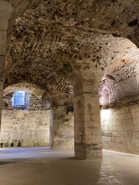 Underground stone structure with arches and pillars.