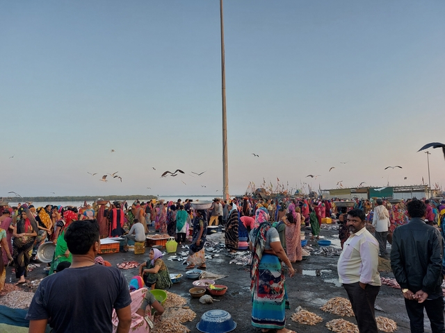 A crowded fish market by the riverside at dawn.