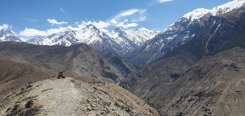 Vast mountainous landscape with snowy peaks under a clear sky.