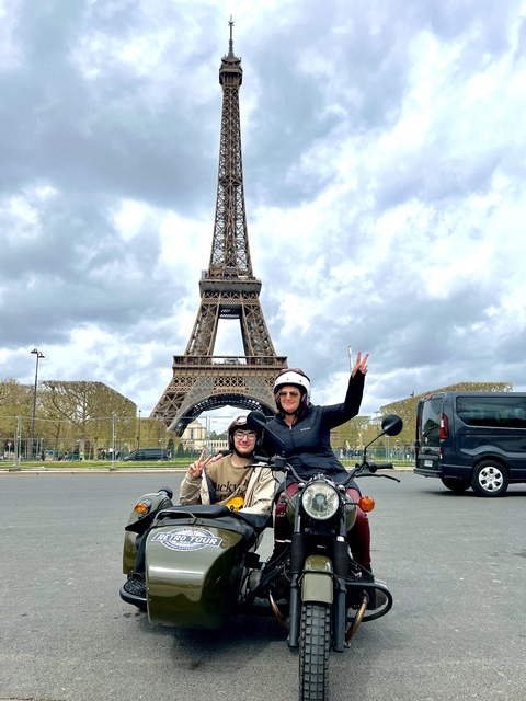 Two people posing with a motorcycle in front of the Eiffel Tower