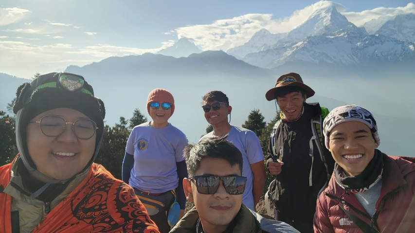 Group of happy trekkers with snowy mountains in the background.