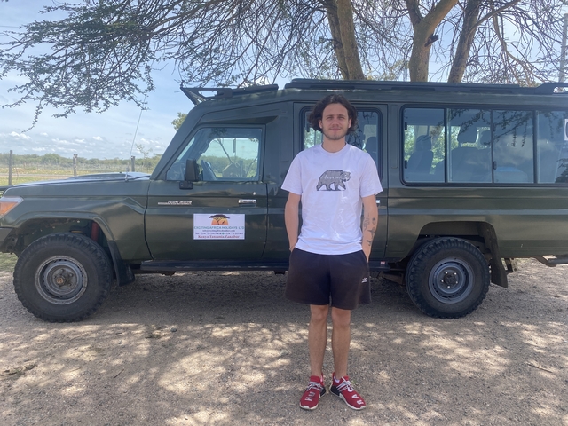 Person standing beside a safari vehicle.