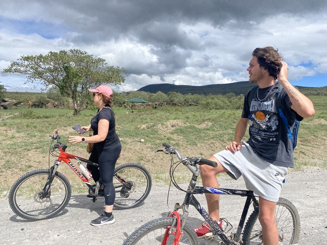 Two people on bikes in a rural setting.