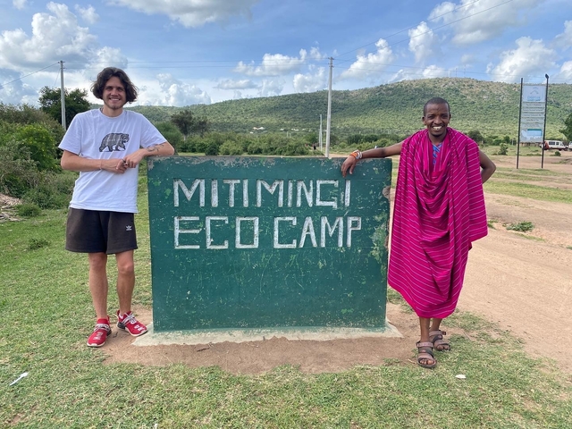 Two men standing next to a sign for Miti Mingi Eco Camp.