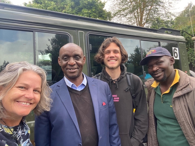 Four people standing beside a green Safari vehicle.