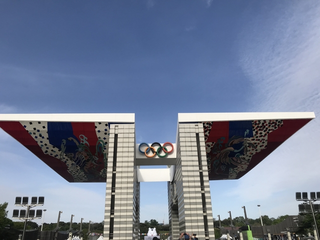 Olympic emblem on a modern structure with clear blue skies.