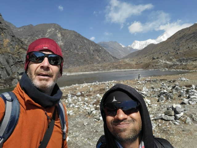 Two people smiling with mountain lake scenery in the background.
