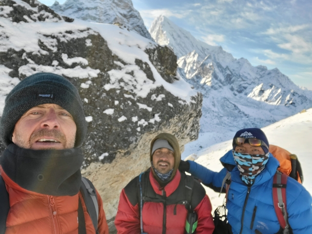 Three people standing on a snow-covered mountain path.