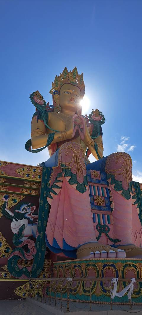 Large golden statue of a deity with mountain backdrop.
