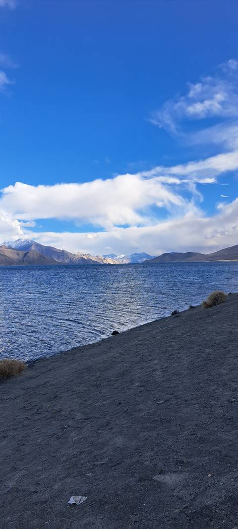 Lake with a rugged shore and cloudy sky.