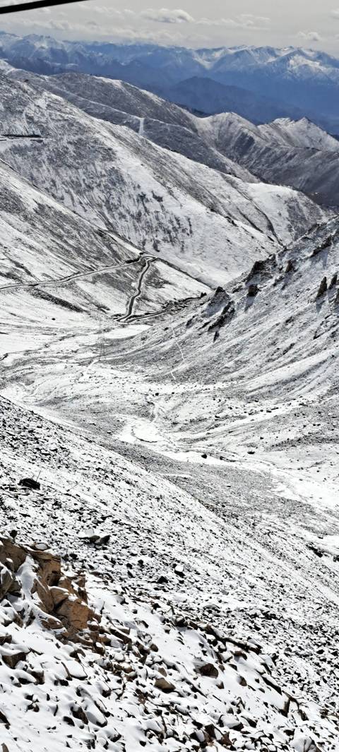 Snow-covered mountain slope with winding roads.