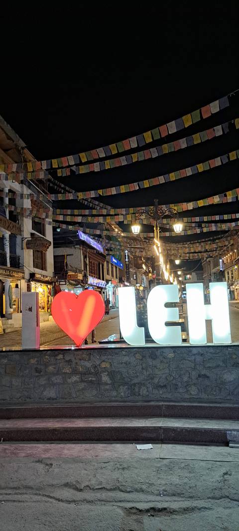 Night scene of lit up city square with signs.