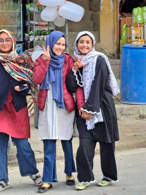 Two women posing on a busy street.