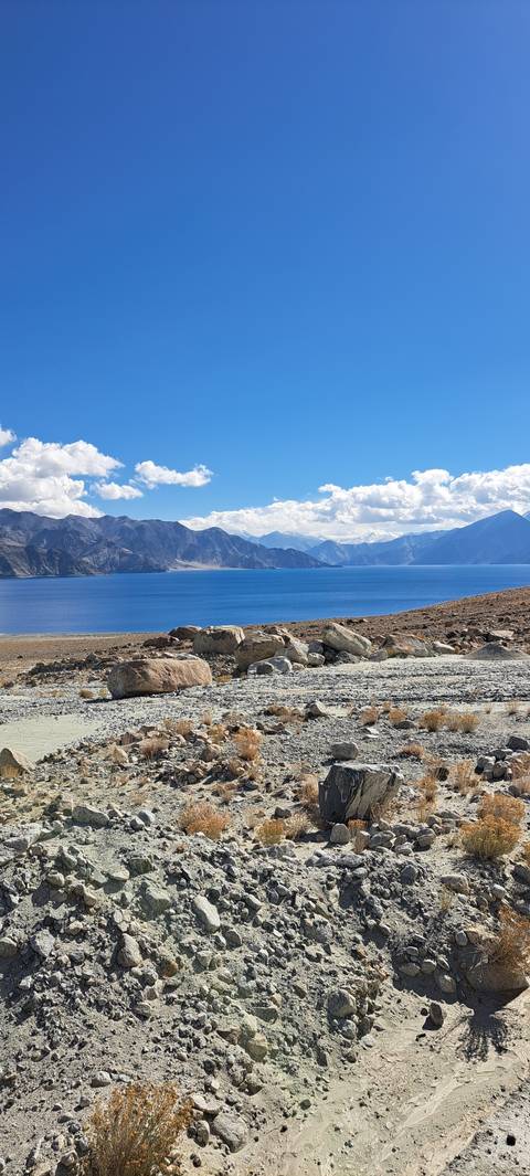 Rocky lakeshore with mountains in the distance.