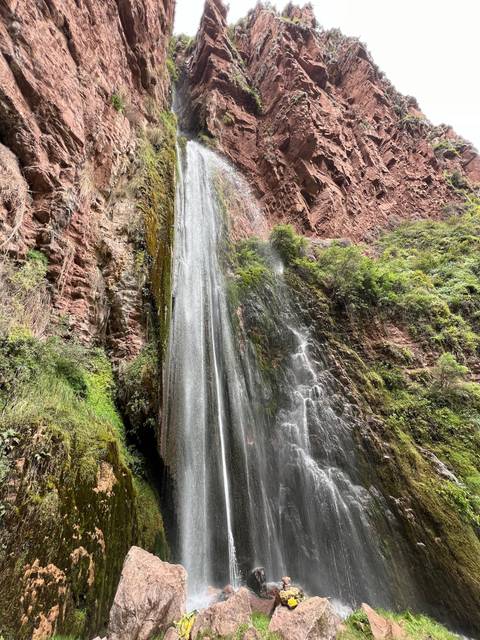 Vertical shot of a waterfall cascading down red rock.