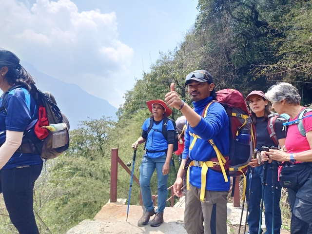 Group of hikers on a mountain trail with greenery in the background.