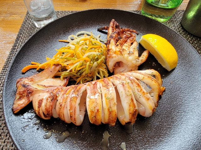 Grilled squid with vegetables on a black plate