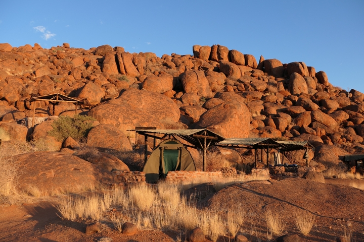 Rustic tents set against a rocky desert landscape.