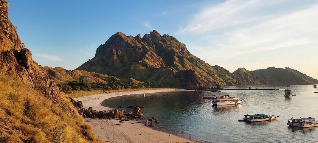 Secluded beach with hills and boats.