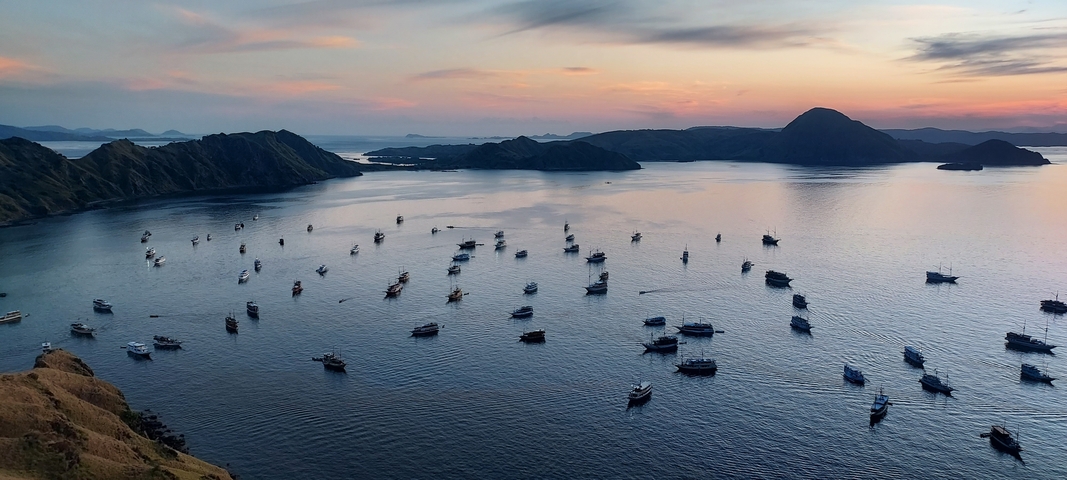 Boats in a bay during sunset with hills.