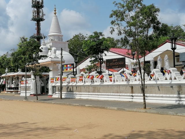 Buddhist temple exterior with flags and statues.