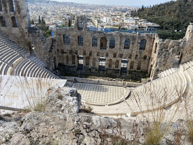 Ancient open-air theater with people standing on the stage.