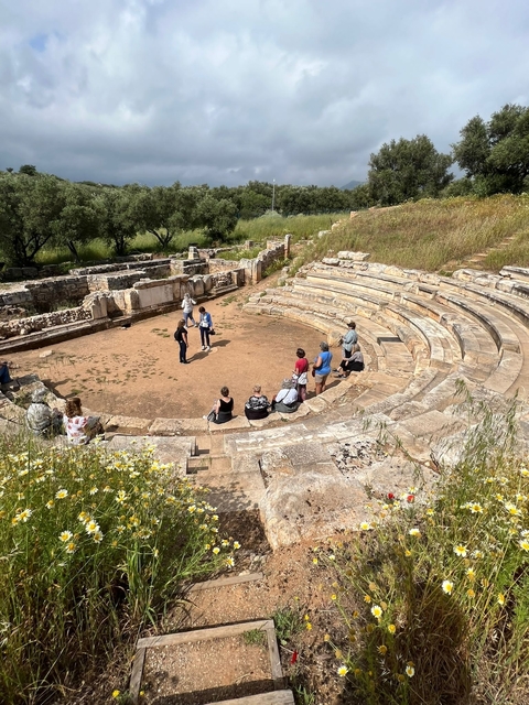 Ancient Greek theater ruins with people touring.