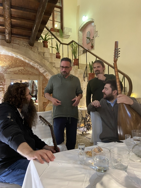 Group of people indoors with musical instruments and talking.