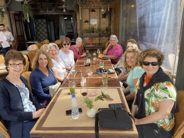 Group of women sitting at a large outdoor dining table.