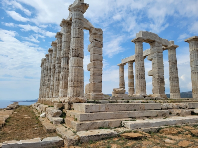 Ancient Greek temple ruins with columns by the sea.
