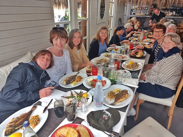 Group of people dining at a restaurant with various dishes.