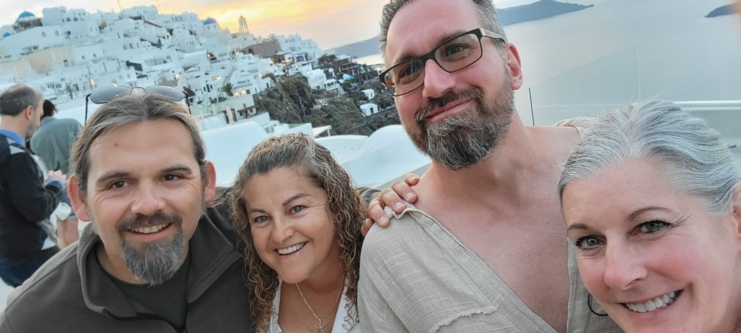 Group selfie with a scenic backdrop of white buildings and sunset.
