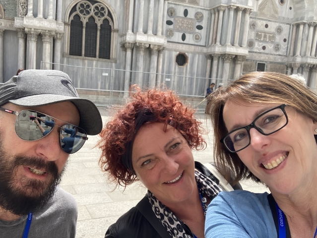 Three people posing in a historic plaza.