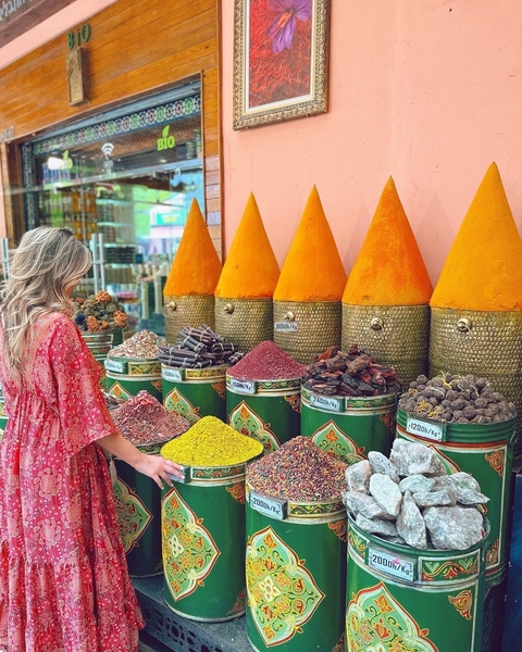 Woman shopping for colorful spices in a market.