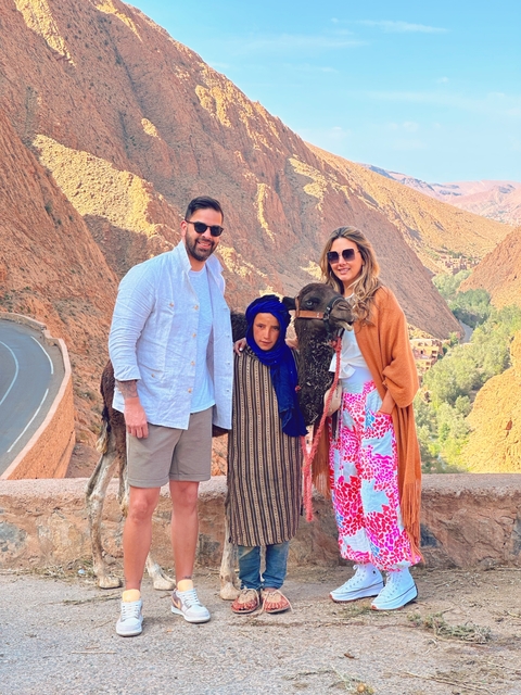 Group posing with a local and a camel in a canyon.