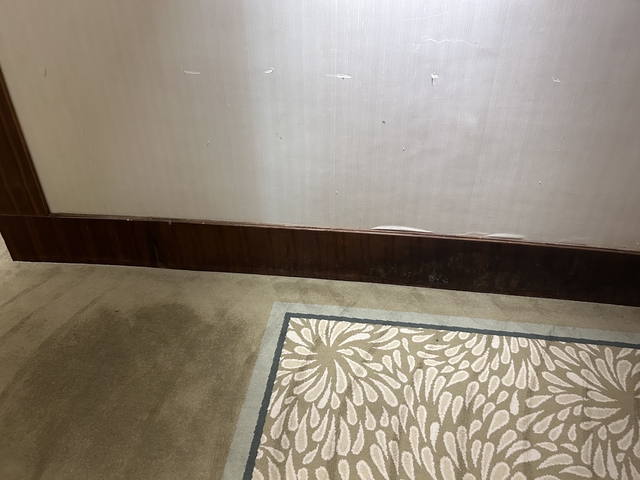 Lower part of a wall with damaged wallpaper.