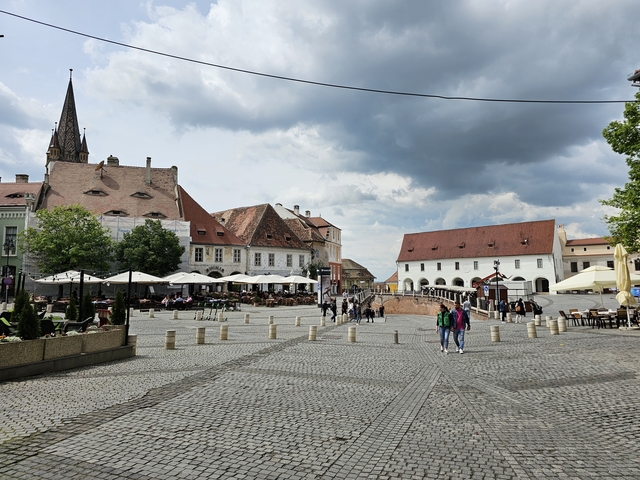 People exploring a historic town square with cobblestone pavement.